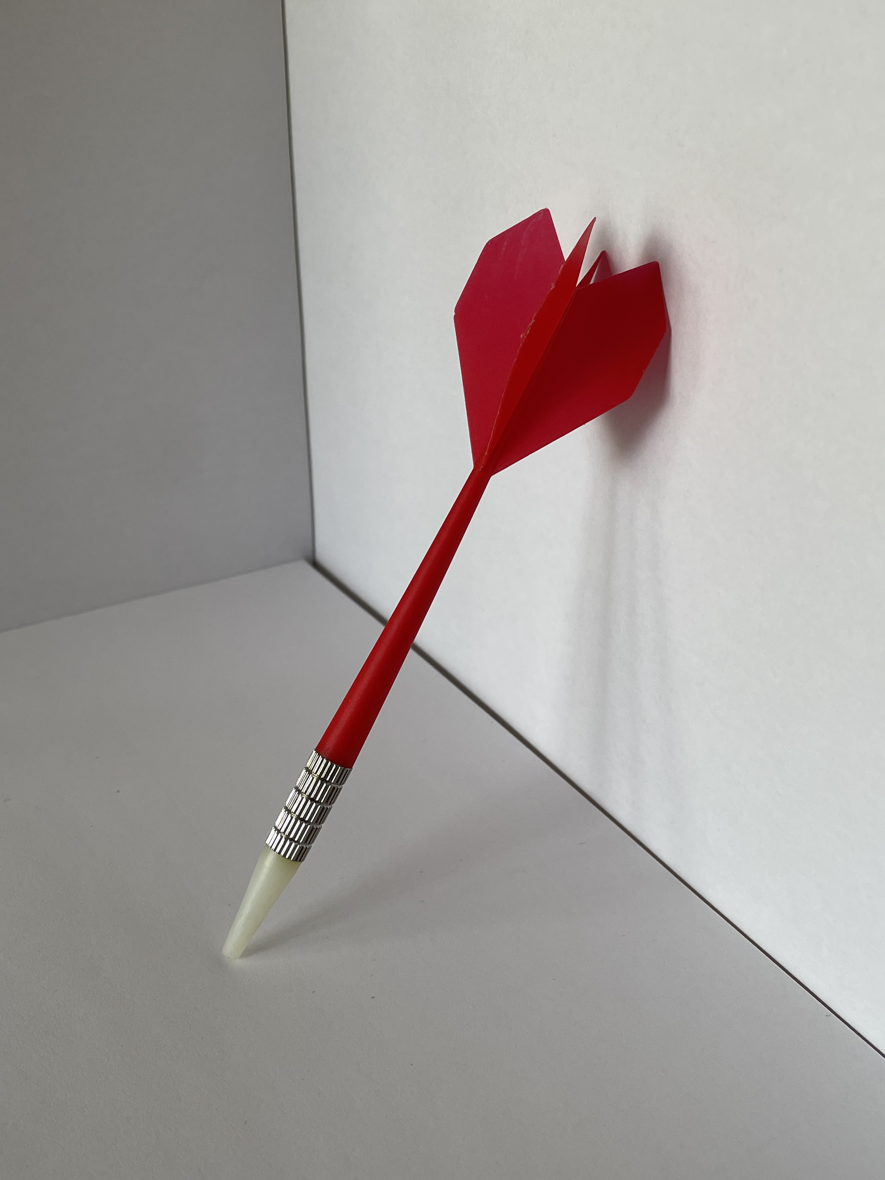 The side view of a dart leaned against a surface.