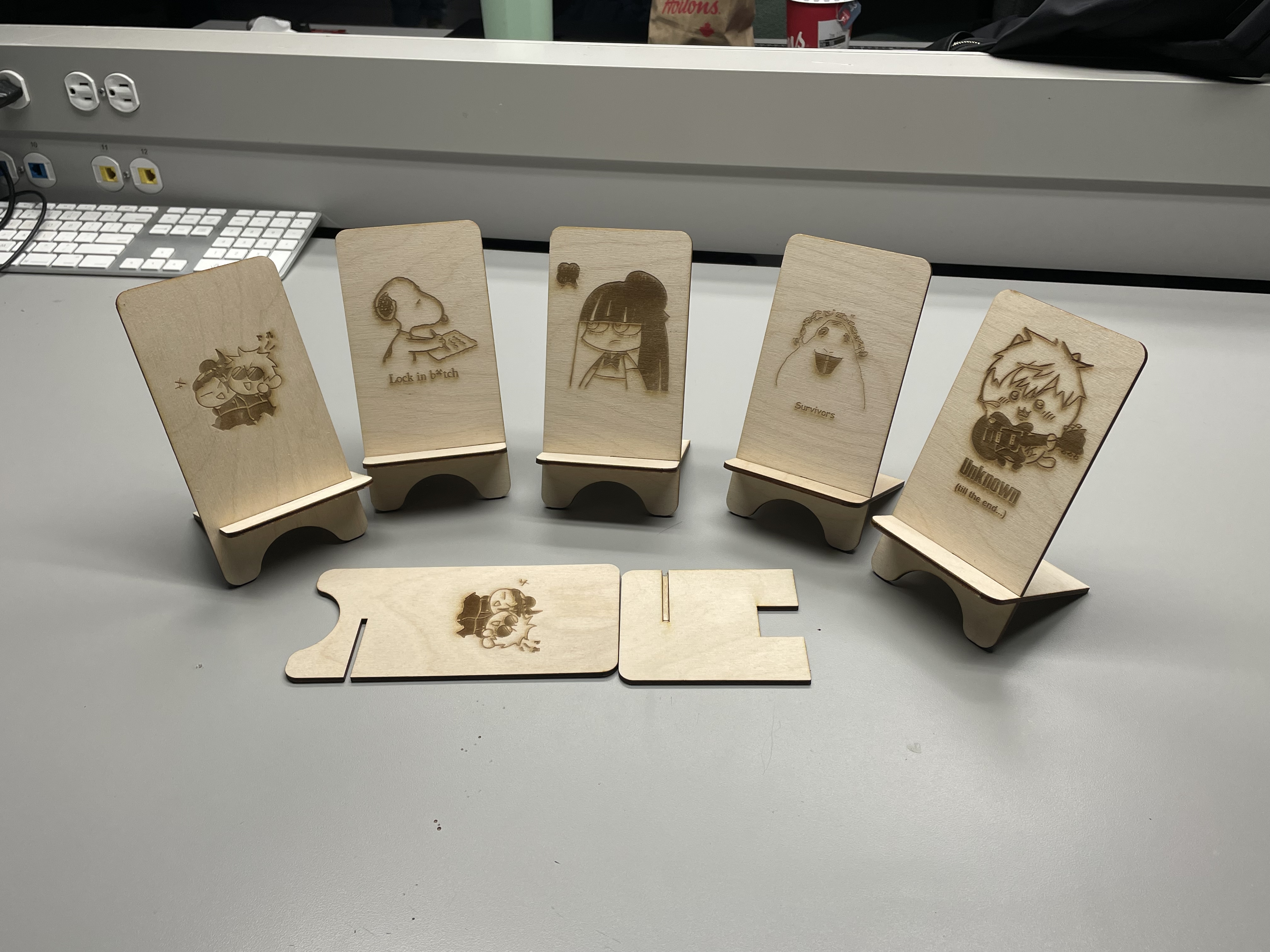 All of our phone stand designs put together. The wood that wasn't cut properly is placed flat on the table.