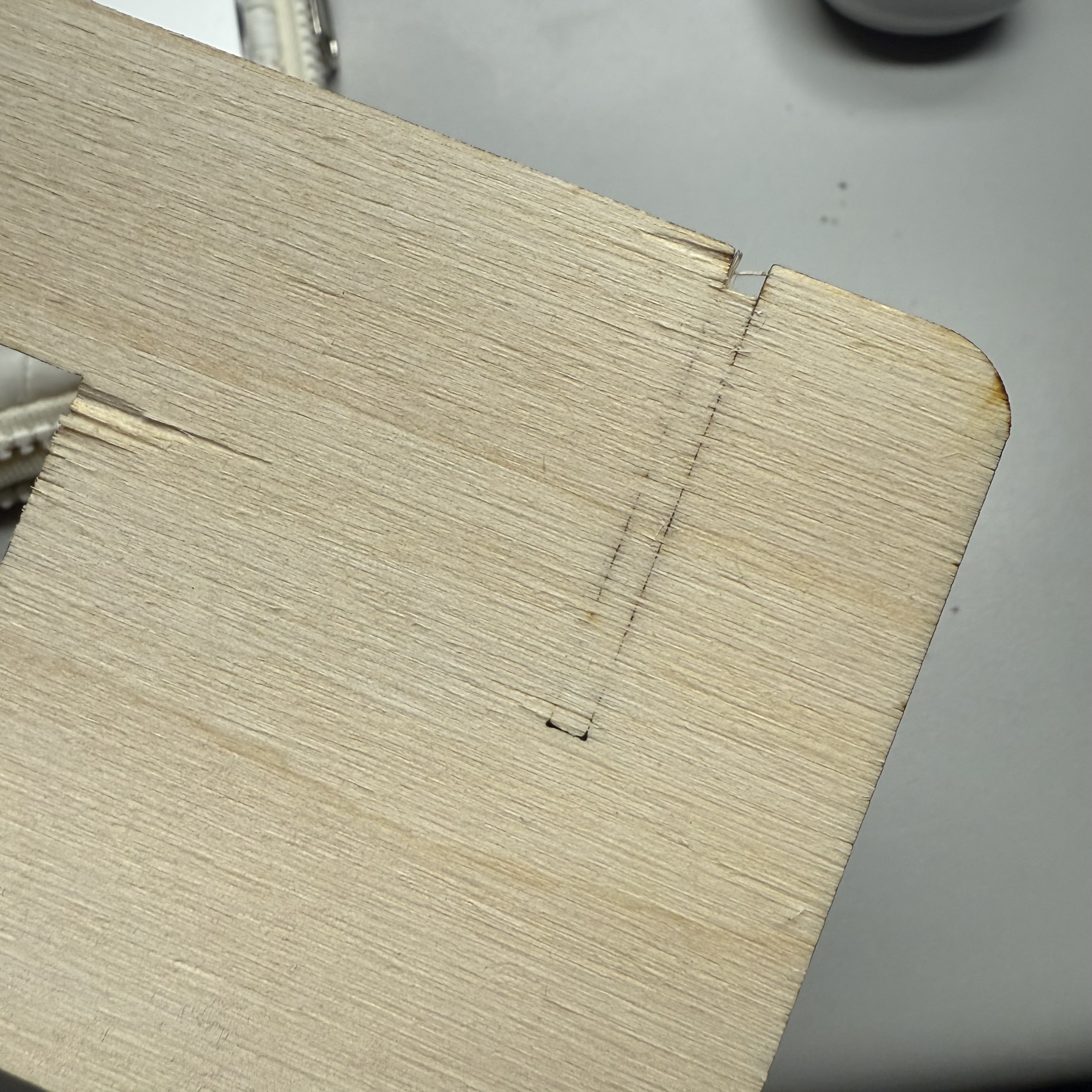 Here is the back side of the back support. The machine didn't cut all the way through. Even when we tried prying out the piece, we were afraid it would break the structure. Marina helped us print another one on the same piece of wood.